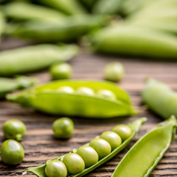 Pods of green peas on a wooden board