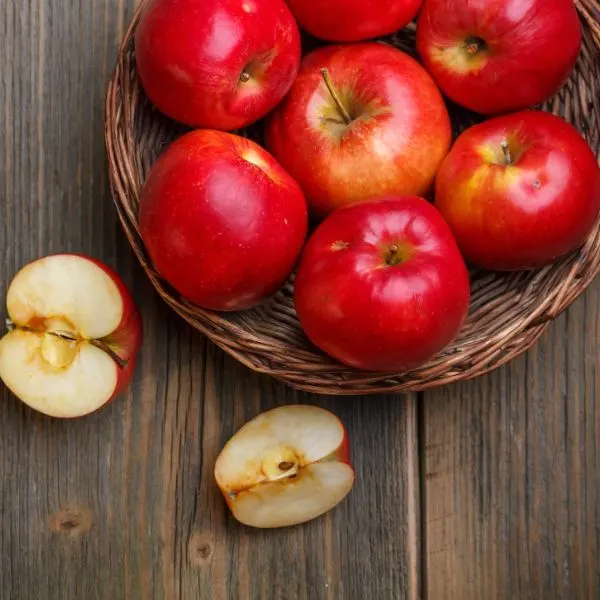 companion plants for trees,red-apples-in-a-basket-with-a-halfcut-apple-on-a-wooden-board